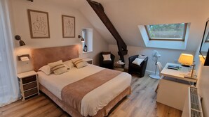 A bedroom with a large bed, a desk with a lamp, a chair, and a window. - Hôtel Le Bellevue (Guer)