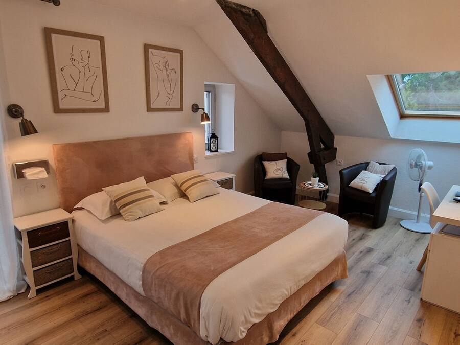 Een slaapkamer met een groot bed, een bureau met een lamp, een stoel en een raam.