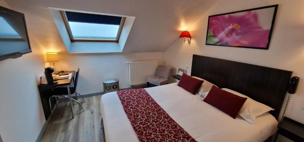 A bedroom with a bed, a desk, a chair, a radiator, a wall-mounted TV, and a skylight.