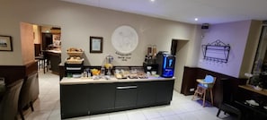 A hotel reception area with a counter, coffee machine, and a wall plaque.