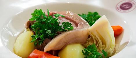 A plate with sliced meat, potatoes, carrots, and parsley.