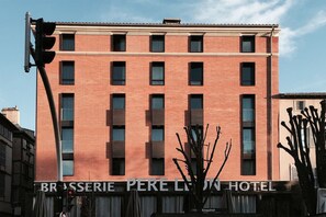 Un hotel de varios pisos con fachada de ladrillo rojo y un cartel que dice "BRASSERIE PERE LION HOTEL".