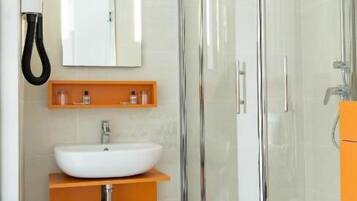 A modern bathroom with a glass-enclosed shower, a white sink, and a toilet.