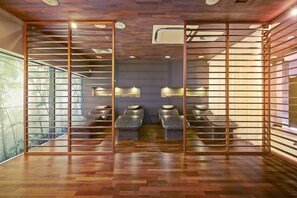 Een spa-ruimte met houten vloeren, een schuifdeur en twee massagetafels.