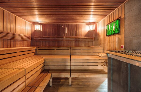 A sauna with wooden benches and a stone wall.