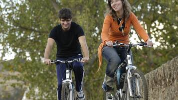 Deux personnes à vélo sur un chemin pavé, avec des arbres en arrière-plan.