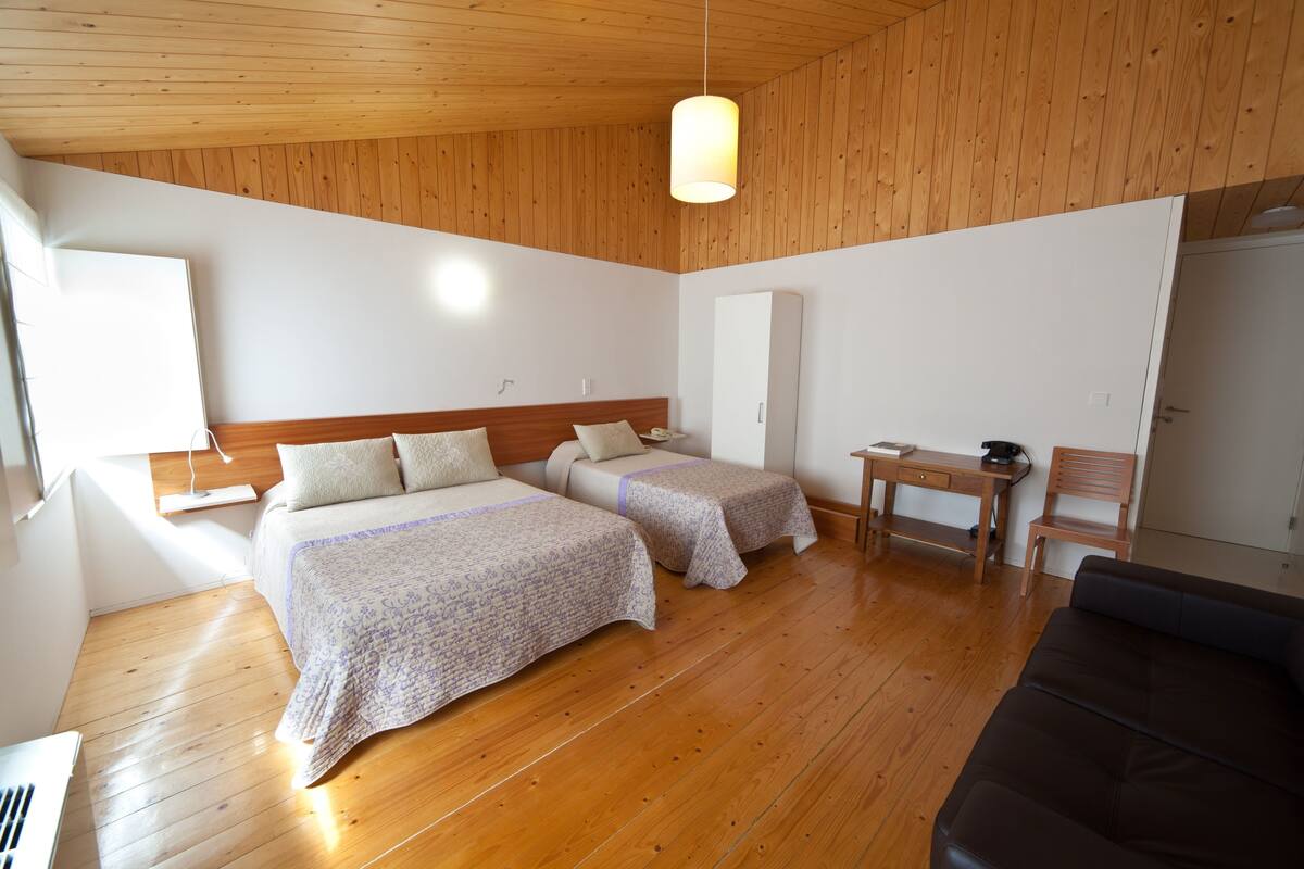 A room with two beds, a desk, a chair, and a sofa.