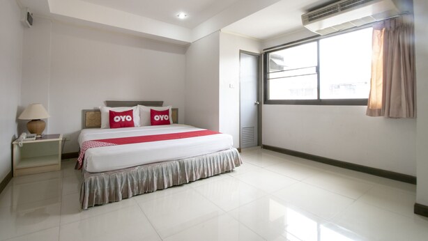 A hotel room with a bed, bedside table, lamp, and a window with curtains. - Hotel Win Long (Bangkok)
