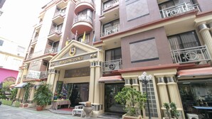 A multi-story hotel with a prominent entrance, balconies, and potted plants. - Hotel Win Long (Bangkok)
