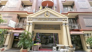 A hotel entrance with a sign reading "WIN LONG PLACE" and a balcony with flags. - Hotel Win Long (Bangkok)