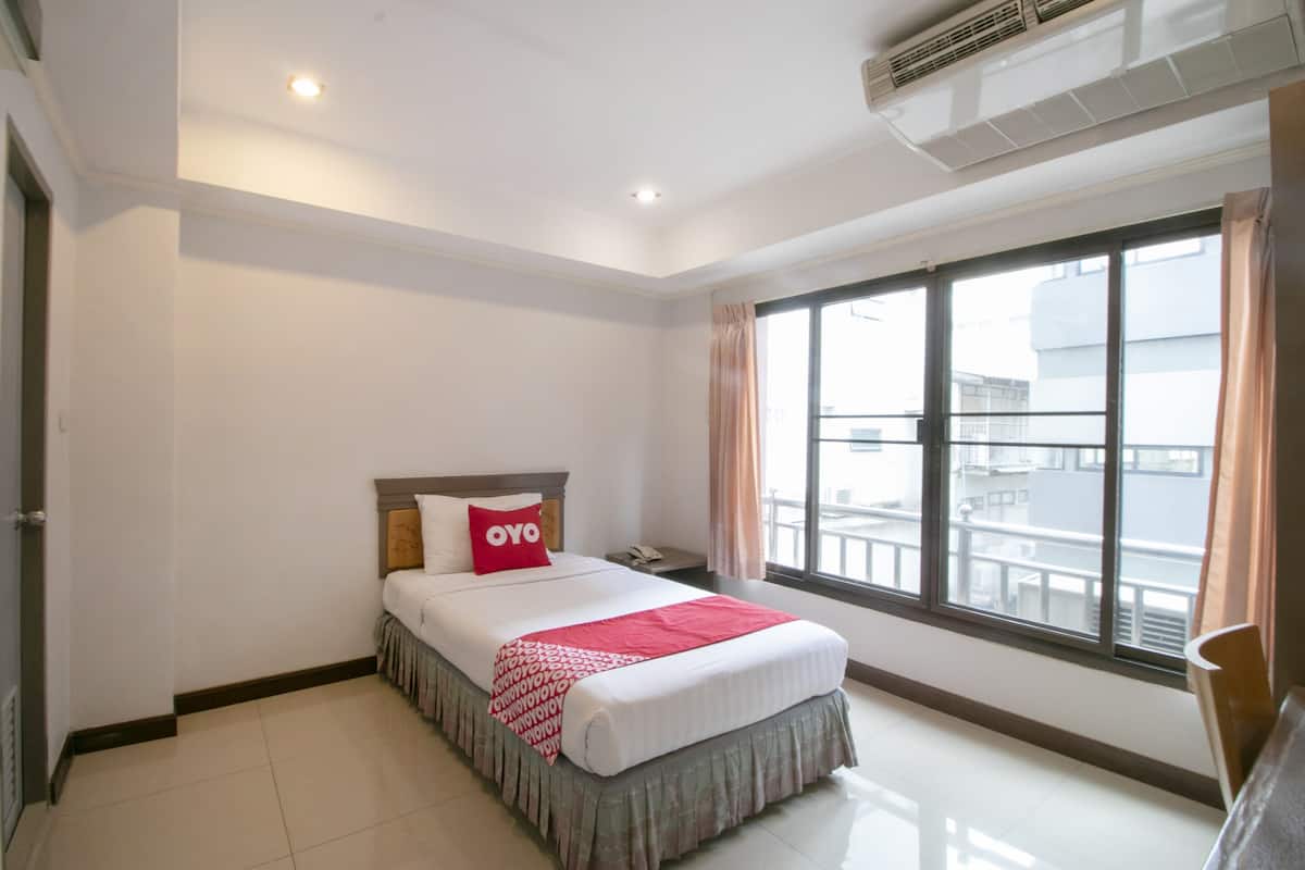 A hotel room with a bed, a window with a view, and a ceiling fan.