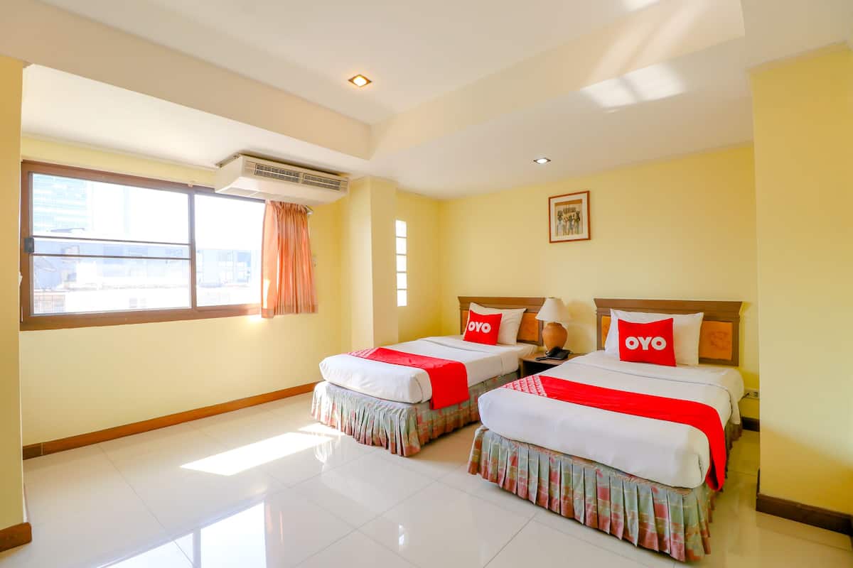 A hotel room with two beds, a large window, an air conditioning unit, and a framed picture on the wall.