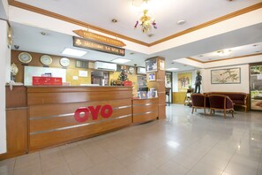 A reception area with a wooden desk displaying the 'OYO' logo, a clock, and a sign for 'Registration & Cashier'. - Hotel Win Long (Bangkok)