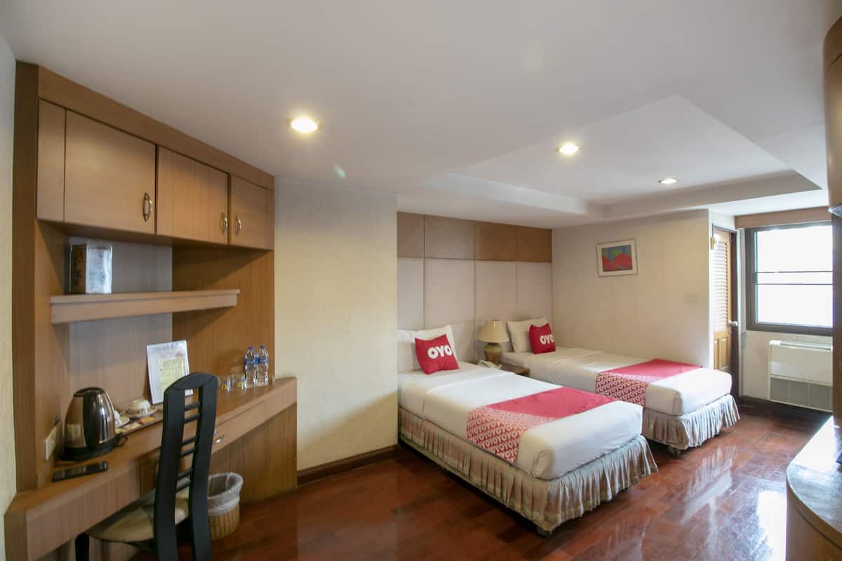 A hotel room with two beds, a desk, and a chair.