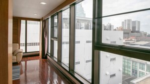 A room with large windows, a wooden floor, and a white wall. - Hotel Win Long (Bangkok)