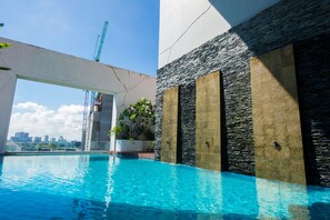 A swimming pool with a view of a city skyline and a construction crane in the background. - Grand Howard Hotel Bangkok (Bangkok)