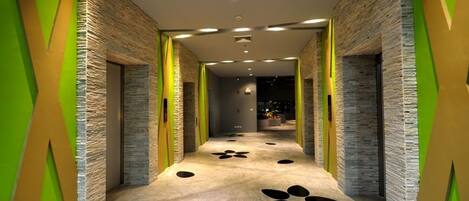 A hallway with stone walls, green accents, and a patterned floor.