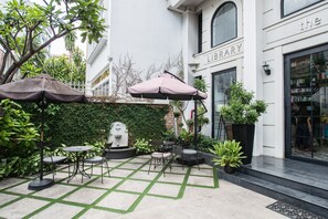 A courtyard with a seating area, a library, and a staircase leading to the entrance. - The Alcove Library Hotel (Ho Chi Minh City)