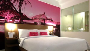 A hotel room with a bed, a nightstand with a lamp, a mirror, and a wall with a tropical mural. - Seminyak Garden (Seminyak)