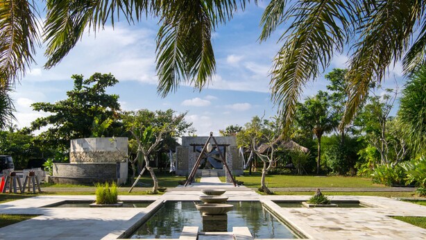 A courtyard with a central water feature, stone benches, and palm trees. - Seminyak Garden (Seminyak)
