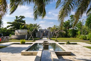 A courtyard with a central water feature, stone benches, and palm trees. - Seminyak Garden (Seminyak)