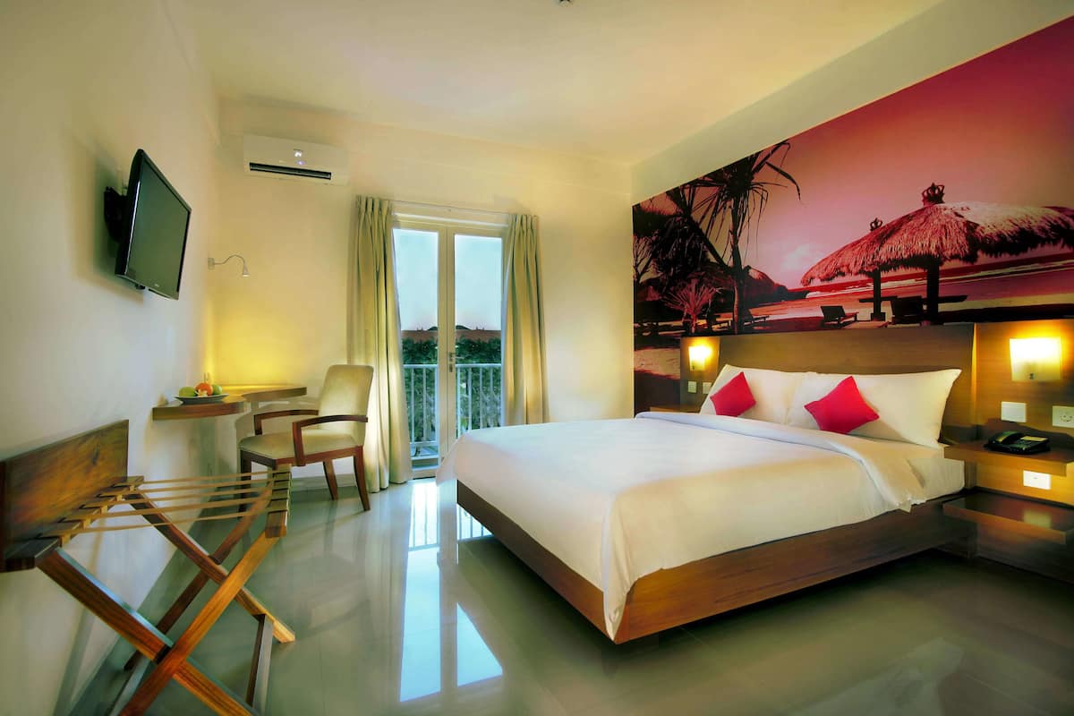 A hotel room with a large bed, a TV mounted on the wall, a balcony with a view, and a painting of a beach scene.