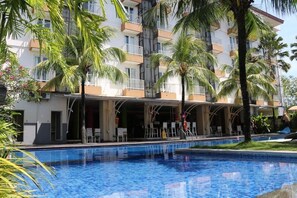 A hotel with a swimming pool, palm trees, and a covered outdoor seating area. - Seminyak Garden (Seminyak)