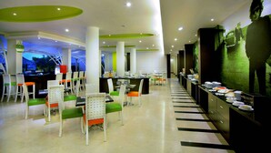 A modern restaurant with white and green chairs, a buffet area, and a view of the outdoors. - Seminyak Garden (Seminyak)