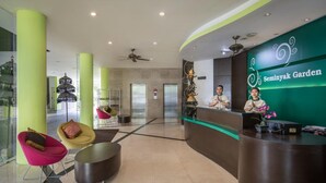 A reception area with a green wall, a reception desk, and two chairs. - Seminyak Garden (Seminyak)