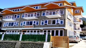 A multi-story hotel with balconies, a sign reading "Hotel Nor Mabal", and a green fence in the foreground. - Hotel Noor Mahal (Anantnag)