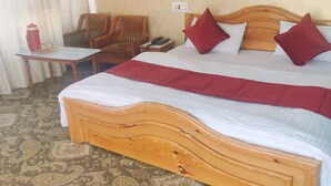 A hotel room with a large bed, wooden headboard, and a patterned carpet. - Hotel Noor Mahal (Anantnag)