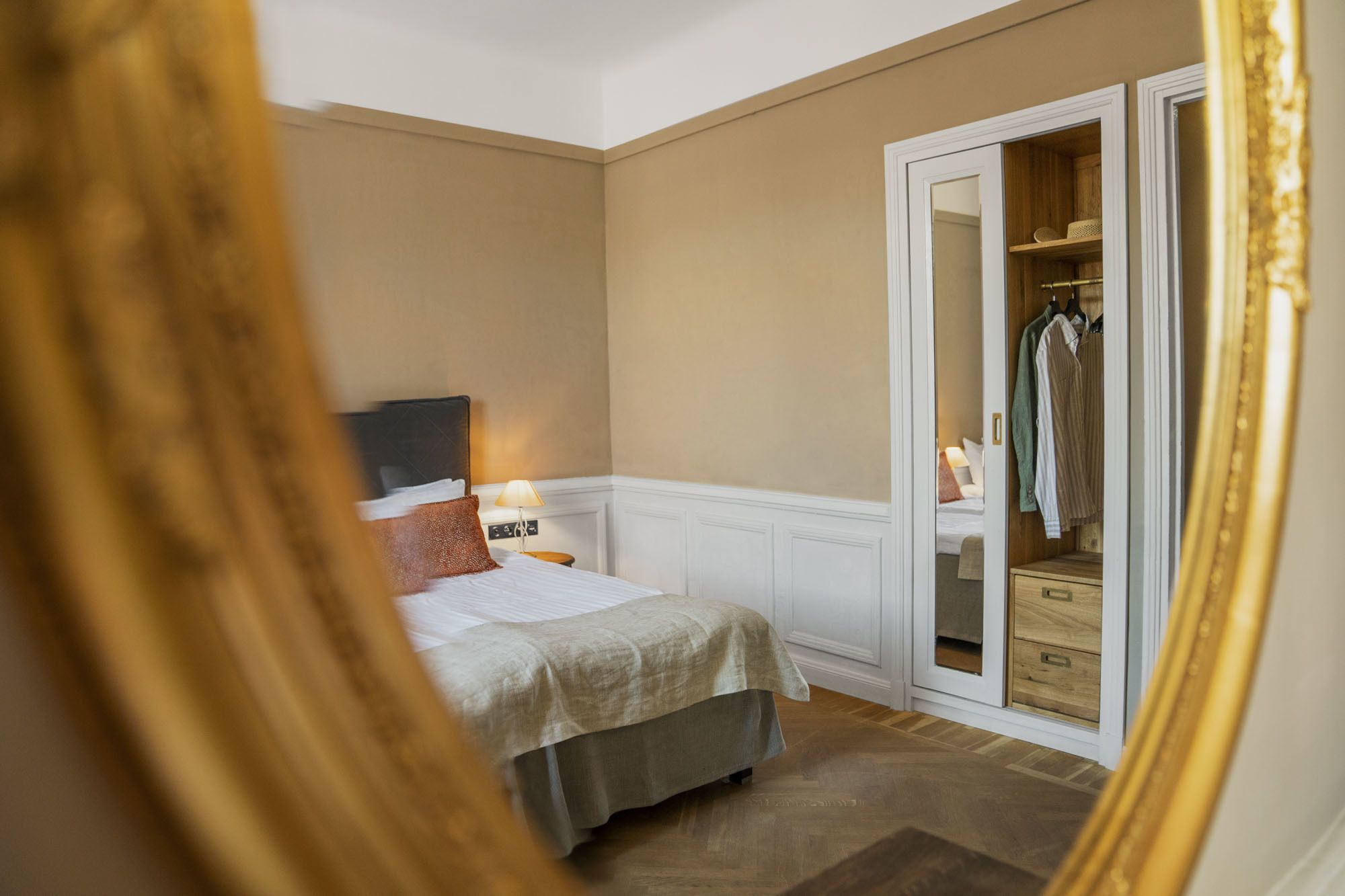 Una camera da letto con un letto, un comodino, una lampada e un armadio pieno di vestiti.