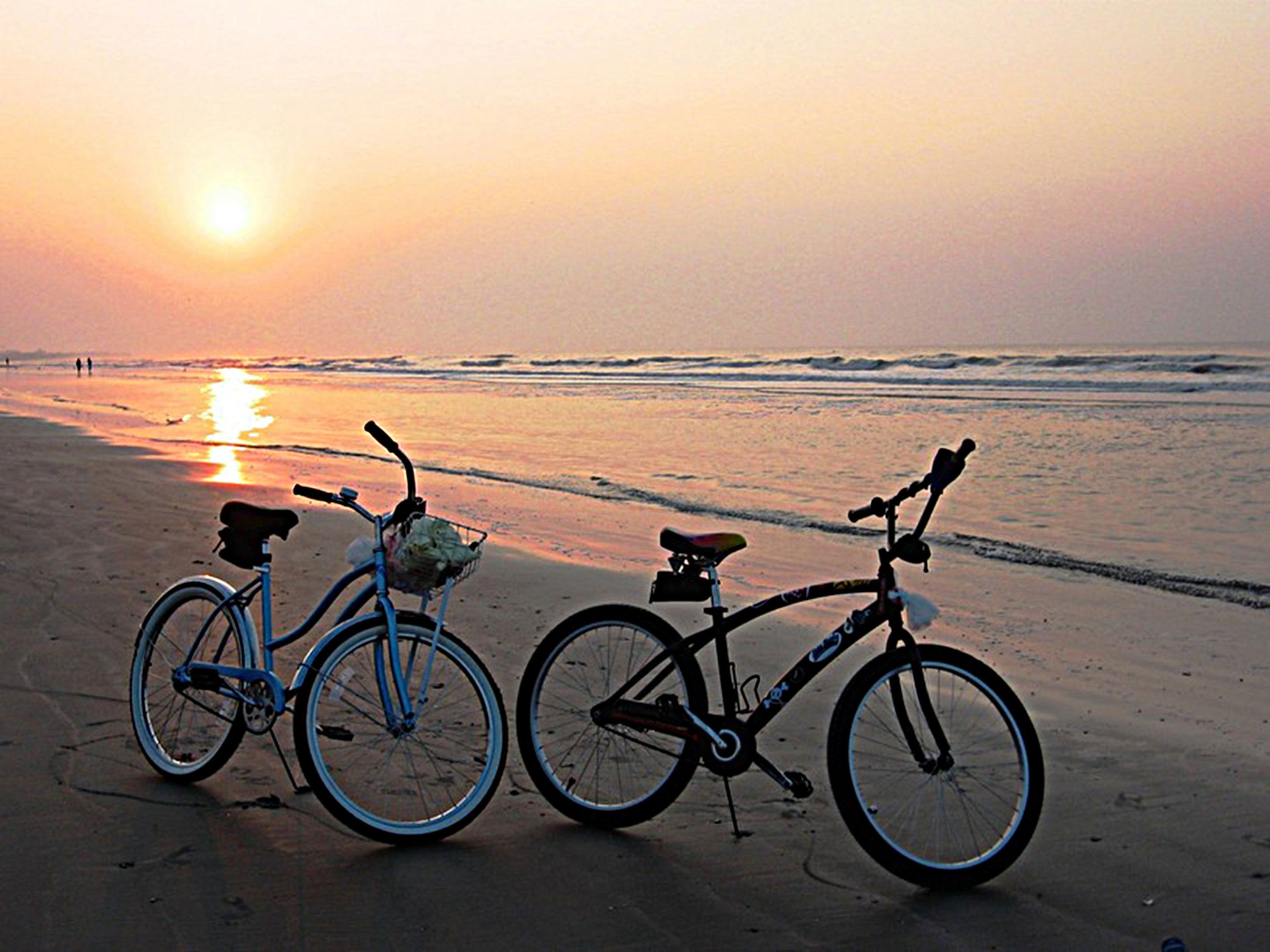 Due biciclette parcheggiate su una spiaggia al tramonto.