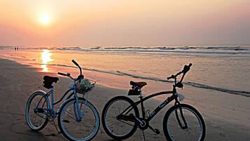 Due biciclette parcheggiate su una spiaggia al tramonto.