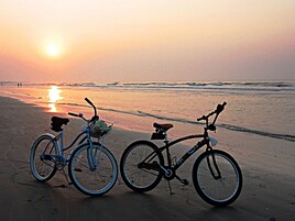 Due biciclette parcheggiate su una spiaggia al tramonto.