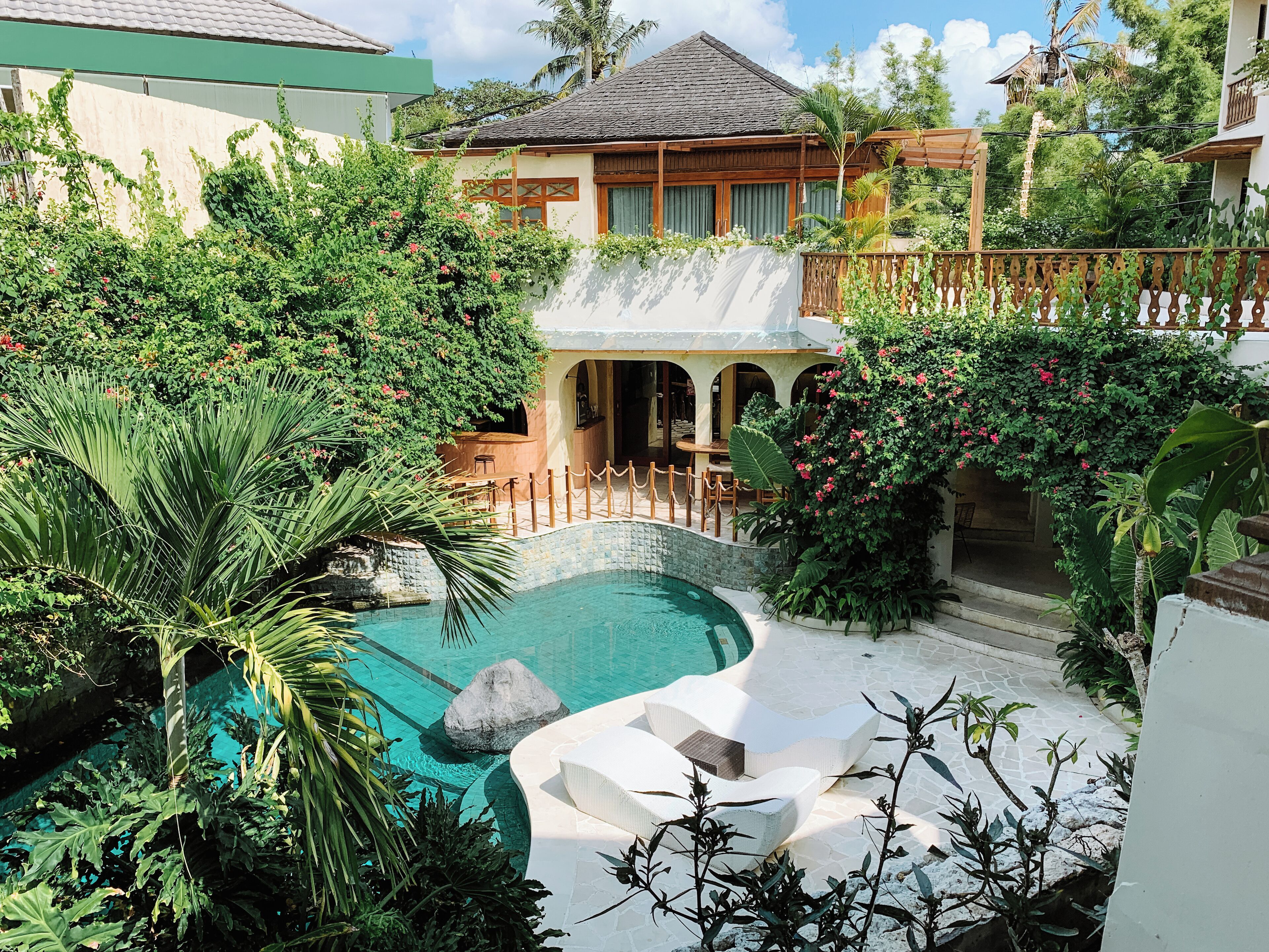 A pool area with a waterfall feature, surrounded by lush greenery and a wooden deck.