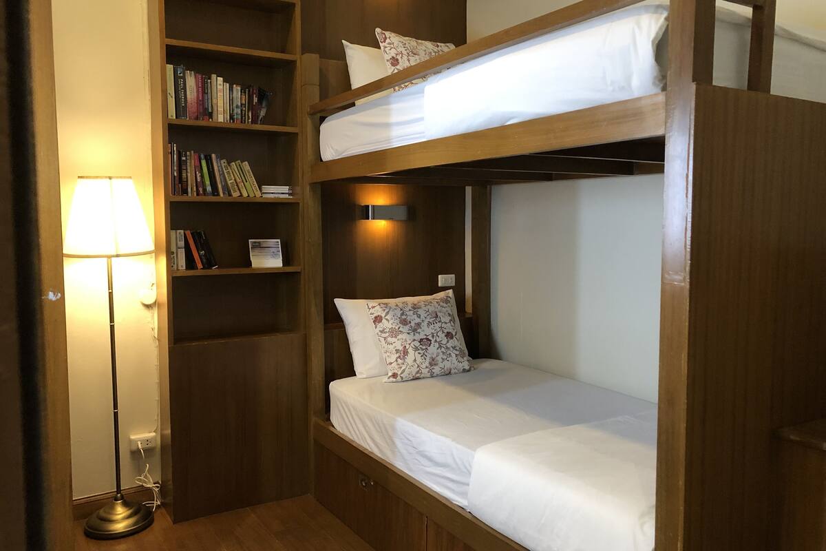 A bunk bed with a bookshelf and a lamp.