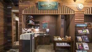 Interior rústico de madera de un restaurante con un letrero, un refrigerador, una barra y una exhibición de revistas.