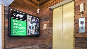 Una pared de madera con un letrero que indica Suneta Hostel Khaosan.