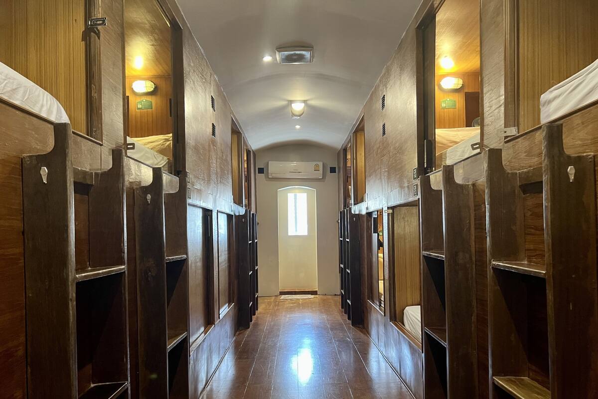 A corridor with wooden lockers and a central door, leading to a room with a window.