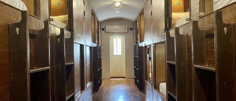 Un pasillo con taquillas de madera y una puerta central, que conduce a una habitación con ventana.