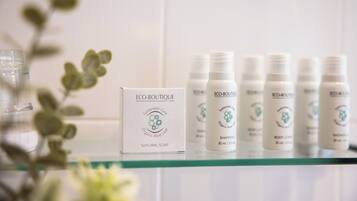 A display of ECO-BOUTIQUE products including natural soap, shampoo, and body lotion on a glass shelf.