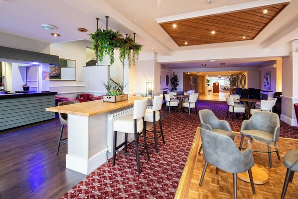 A modern hotel lobby with a bar area, seating, and a reception desk. - The Norfolk Lodge Hotel (St. Helier)