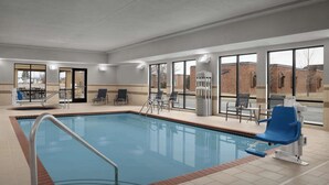 An indoor swimming pool with a clear view of the outside, a poolside seating area, and a lifeguard chair. - Hampton Inn & Suites Williston (Williston)