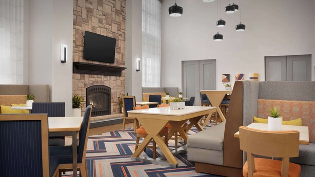 A modern hotel lobby with a fireplace, seating areas, and a flat-screen TV mounted on the wall. - Hampton Inn & Suites Williston (Williston)