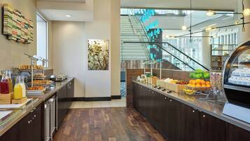 A modern breakfast area with a buffet, wooden flooring, a staircase, and a view of the outdoors.