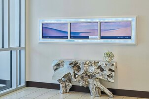 Un interior moderno con una consola de madera original y dos pantallas digitales enmarcadas en la pared.