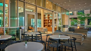 An indoor/outdoor seating area with tables and chairs, a fire pit, and a bookshelf. - SpringHill Suites by Marriott Denver Downtown (Denver)