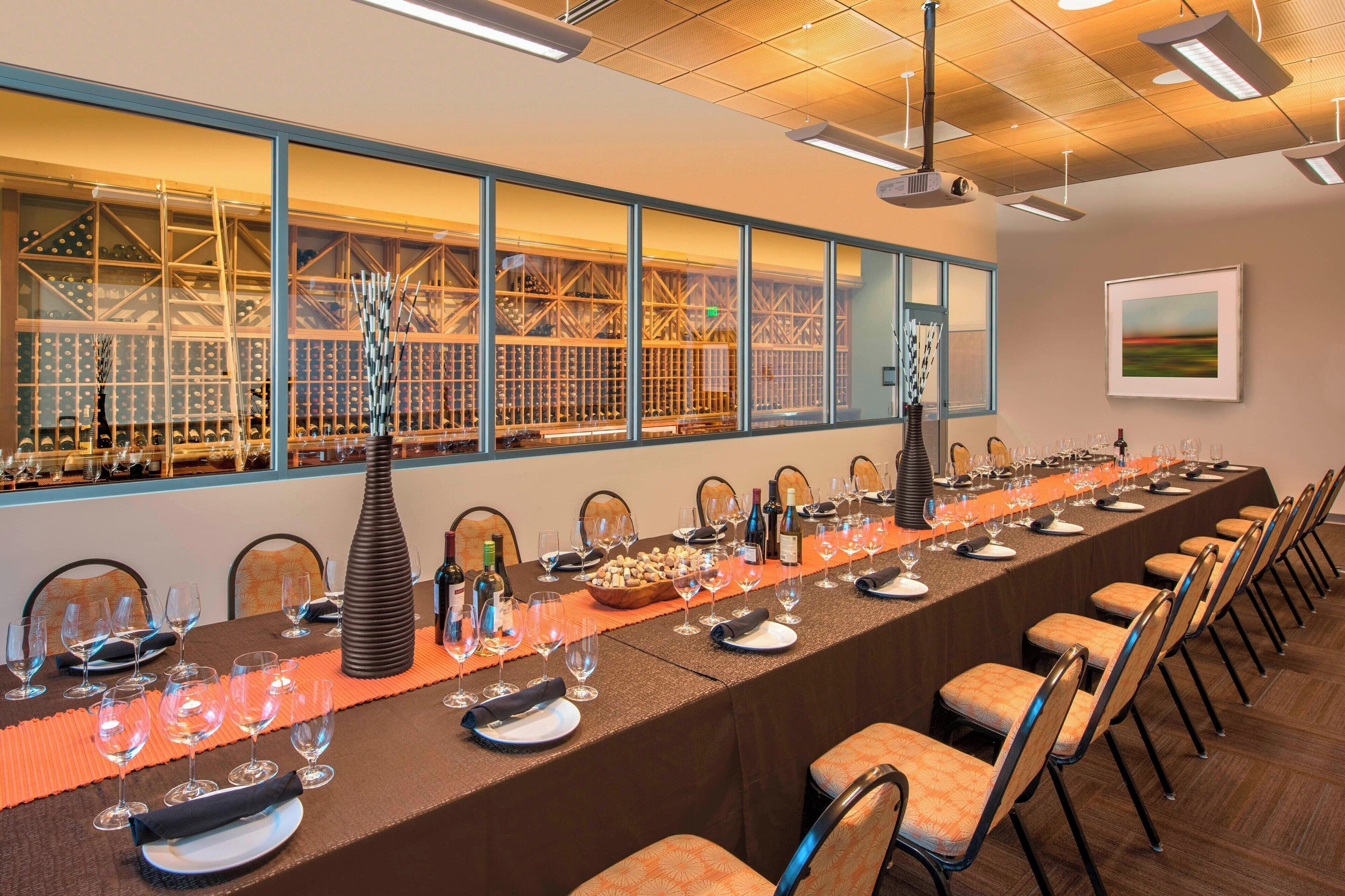 A long dining table set for a formal event with wine glasses, plates, and a centerpiece.