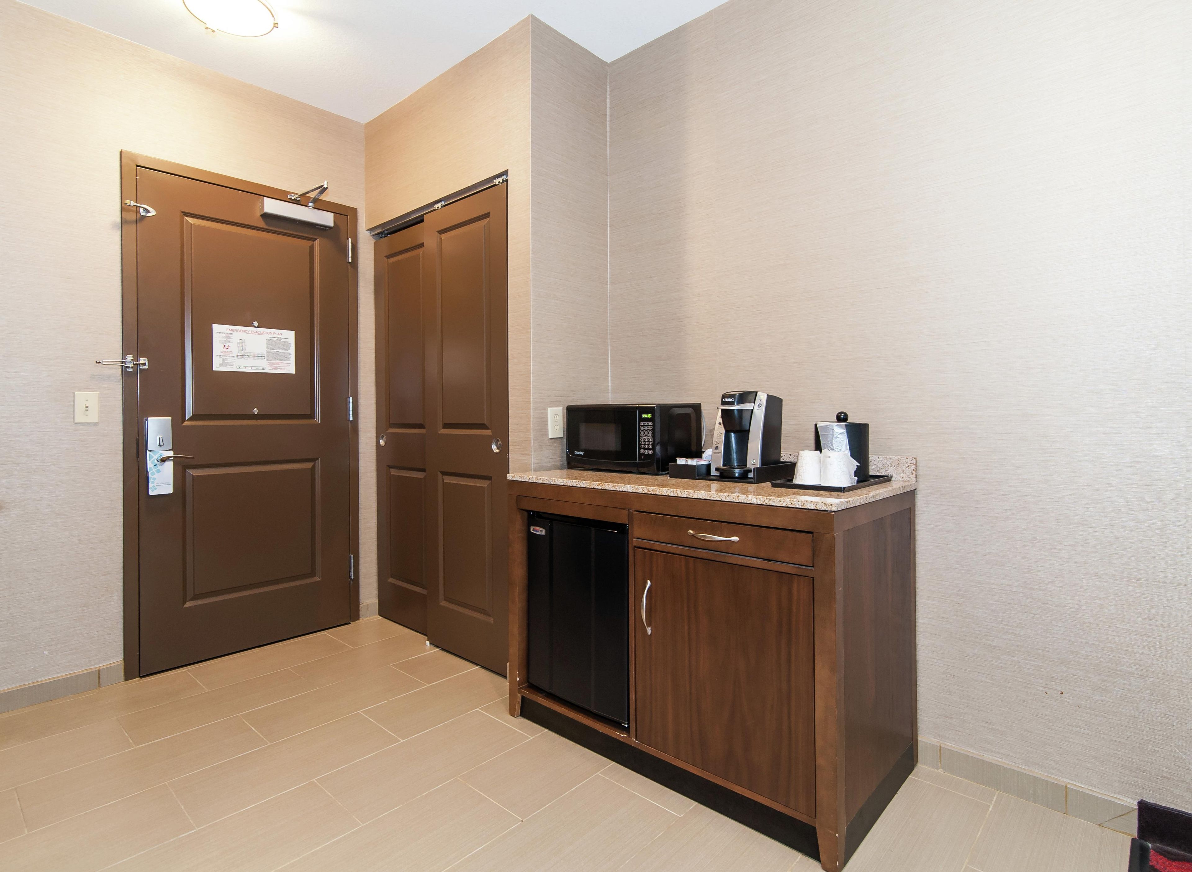 A kitchenette with a microwave, coffee maker, and a cabinet.